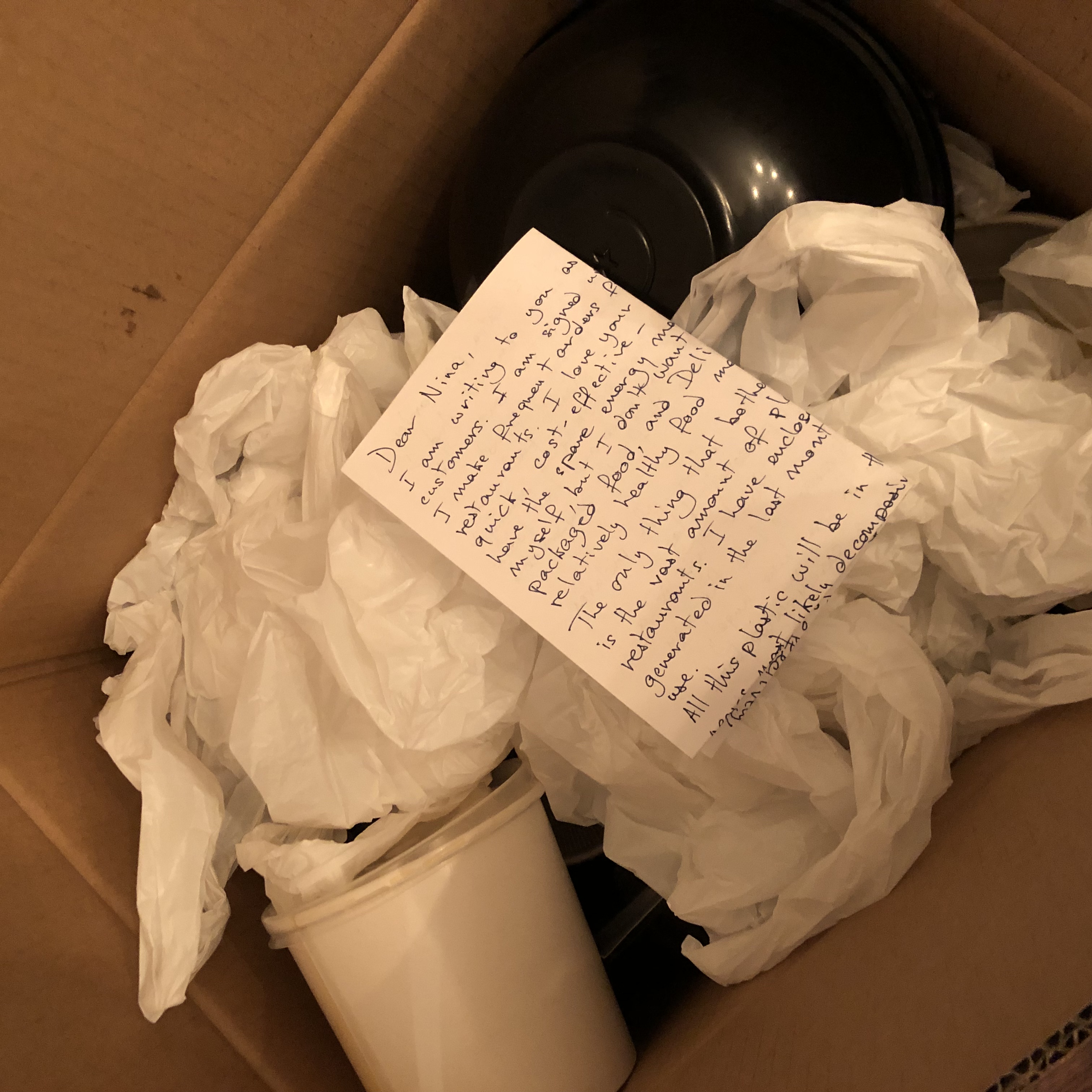 The hand-written letter, folded neatly, on top of the plastics in the box